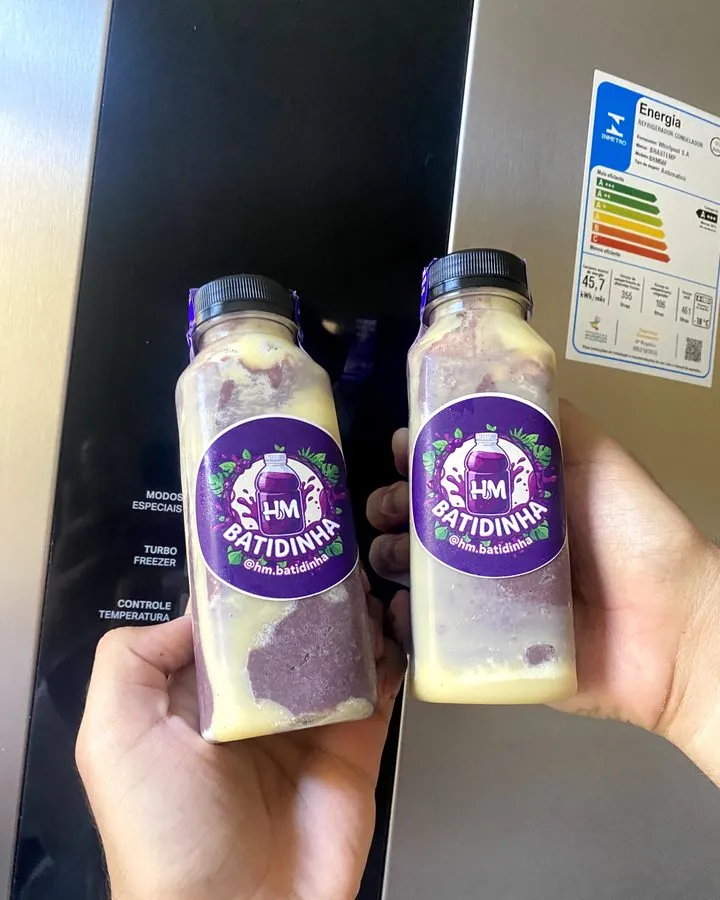 Duas garrafinhas HM Batidinha de açaí com creme, uma em cada mão (abre o Instagram)